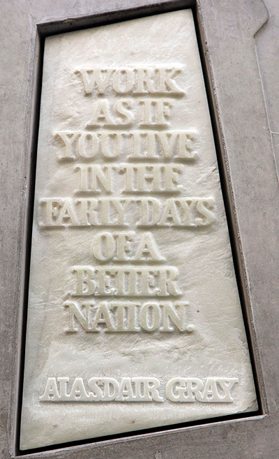 Stone with the following words carved on it: "Work as if you live in the early days of a better nation. Alasdair Gray"