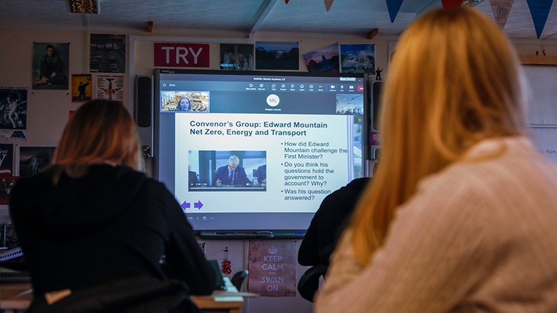 School pupils looking at a presentation on a screen at the front of a classroom
