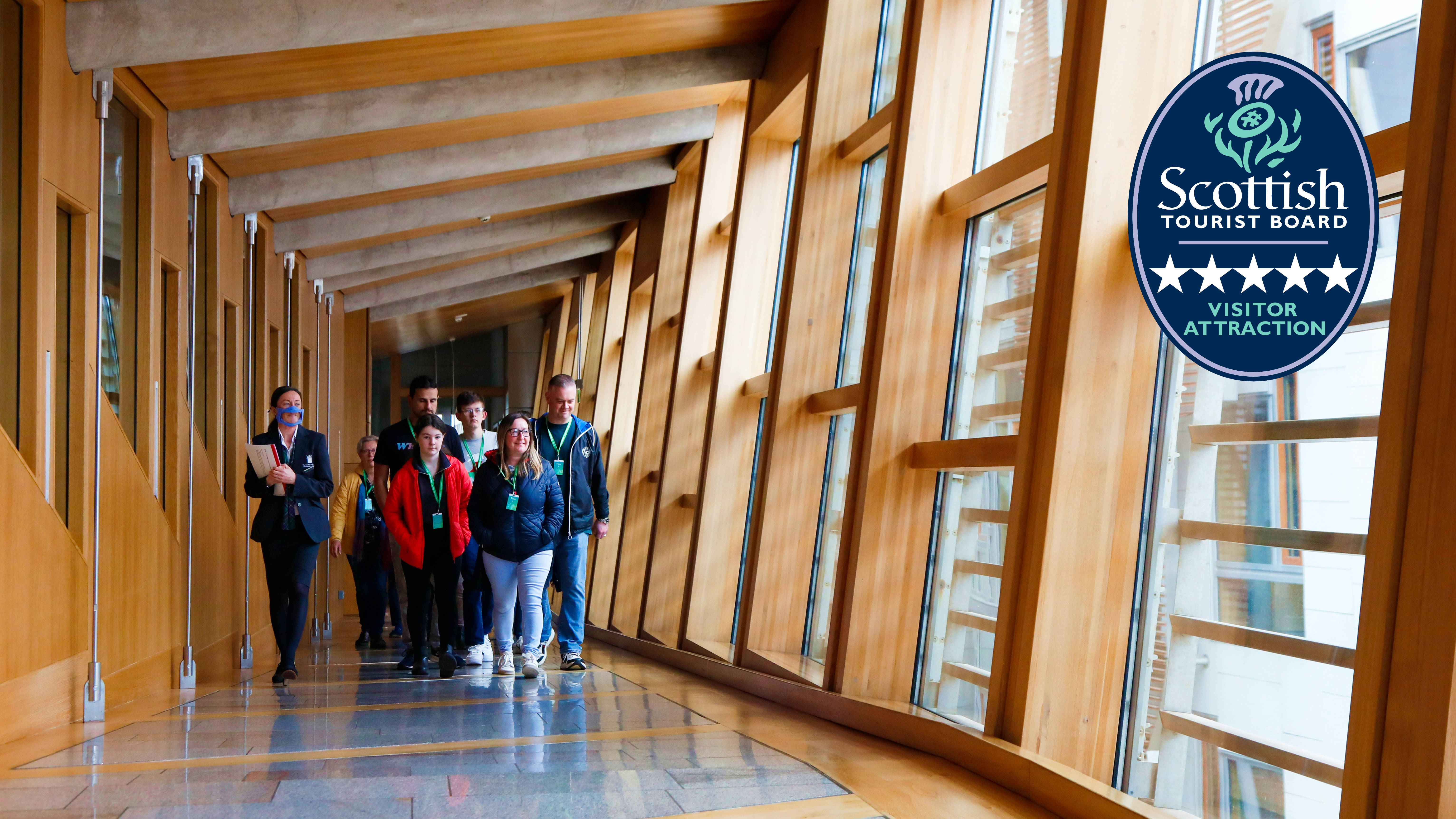A group of visitors are led up the glass corridor by a tour guide
